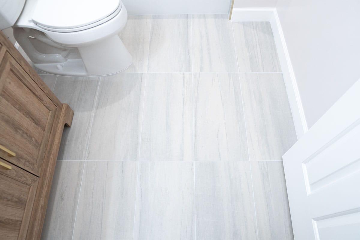 Wide view of new light gray ceramic flooring installed in a Rockville home hallway bathroom